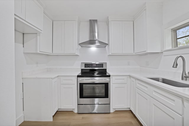 kitchen featuring white cabinetry, wall chimney range hood, sink, and stainless steel electric range oven