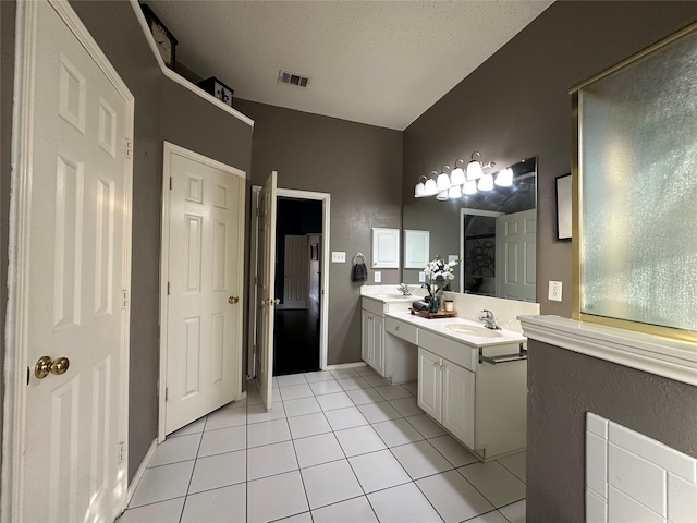 bathroom with tile patterned flooring, a textured ceiling, and vanity