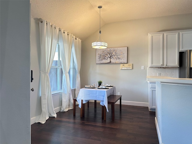 dining room with a textured ceiling, dark hardwood / wood-style floors, and vaulted ceiling