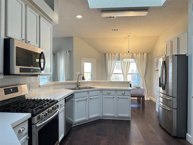 kitchen featuring hanging light fixtures, dark hardwood / wood-style floors, kitchen peninsula, lofted ceiling, and appliances with stainless steel finishes