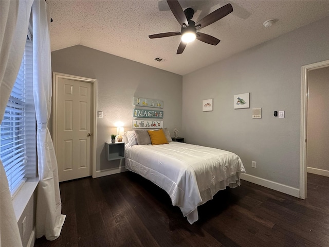 bedroom with a textured ceiling, vaulted ceiling, ceiling fan, and dark wood-type flooring