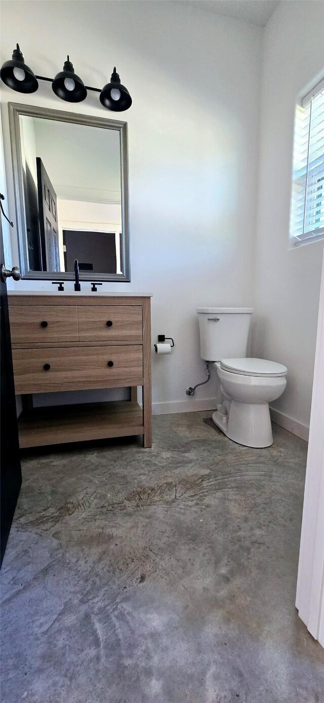 bathroom featuring concrete flooring, vanity, and toilet