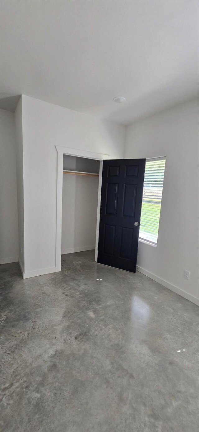 unfurnished bedroom featuring a closet and concrete flooring