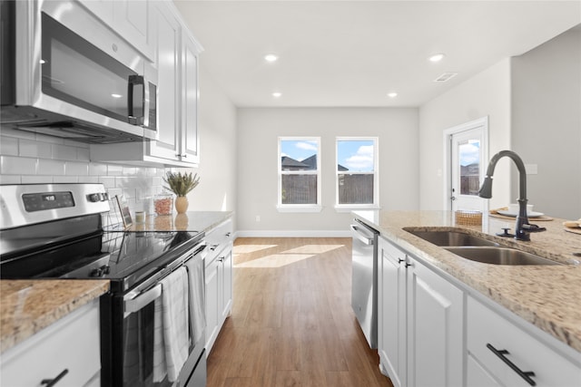 kitchen featuring sink, white cabinets, stainless steel appliances, and light hardwood / wood-style floors