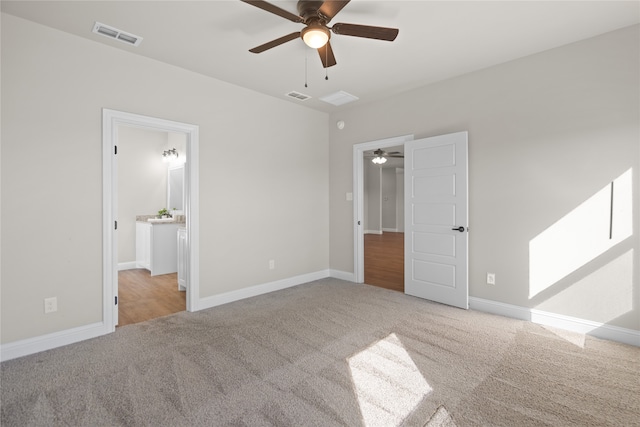 unfurnished bedroom featuring light colored carpet, ensuite bath, and ceiling fan