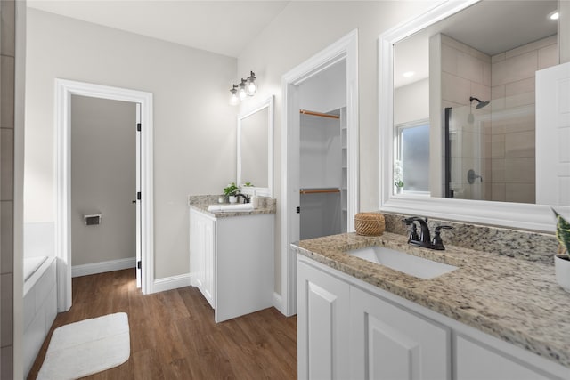 bathroom featuring wood-type flooring, vanity, and a tile shower