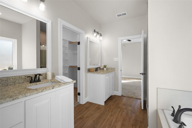 bathroom with wood-type flooring, vanity, and a tub to relax in