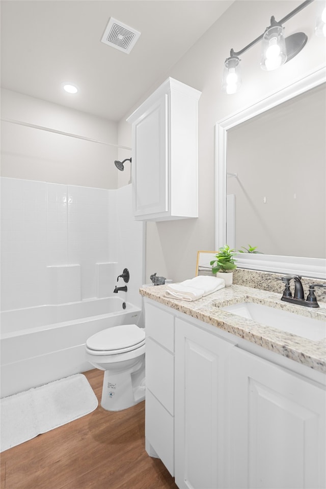 full bathroom featuring washtub / shower combination, toilet, wood-type flooring, and vanity