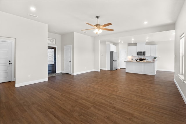 unfurnished living room featuring ceiling fan and dark wood-type flooring