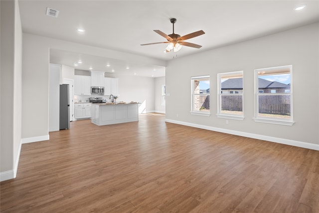 unfurnished living room featuring light hardwood / wood-style floors, ceiling fan, and sink