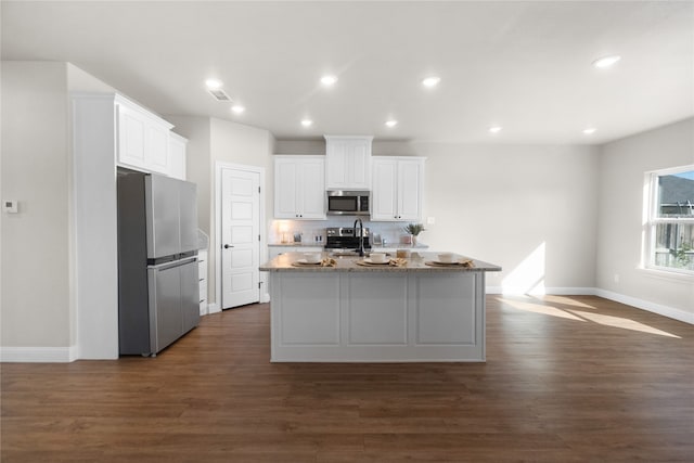 kitchen with a kitchen island with sink, dark wood-type flooring, white cabinets, and stainless steel appliances