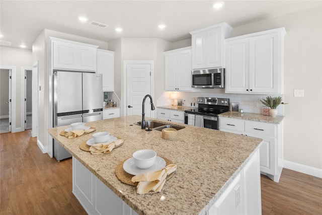 kitchen featuring light hardwood / wood-style floors, sink, stainless steel appliances, and an island with sink