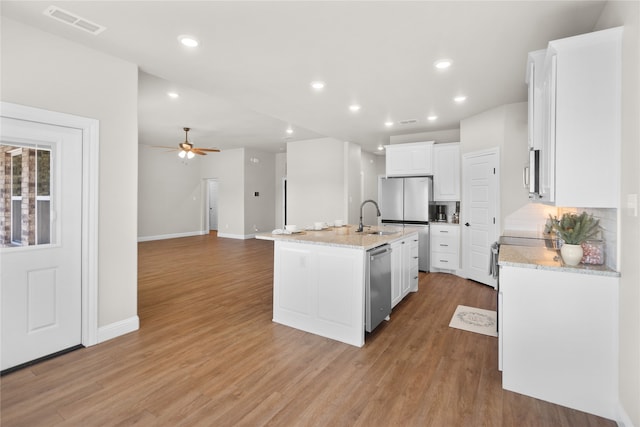 kitchen with a kitchen island with sink, white cabinets, light hardwood / wood-style flooring, ceiling fan, and stainless steel appliances