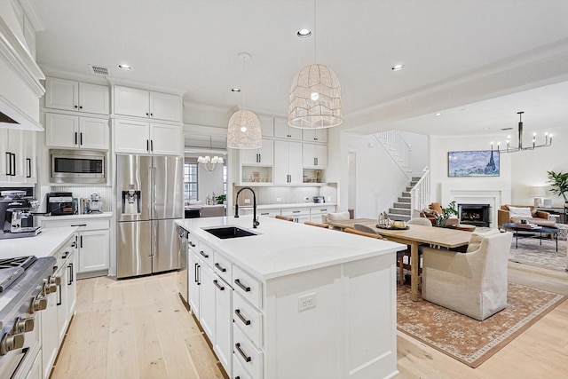 kitchen with light wood finished floors, a fireplace, stainless steel appliances, and a sink