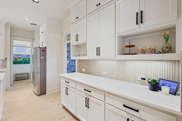 kitchen featuring light wood-style flooring, freestanding refrigerator, light countertops, white cabinetry, and open shelves