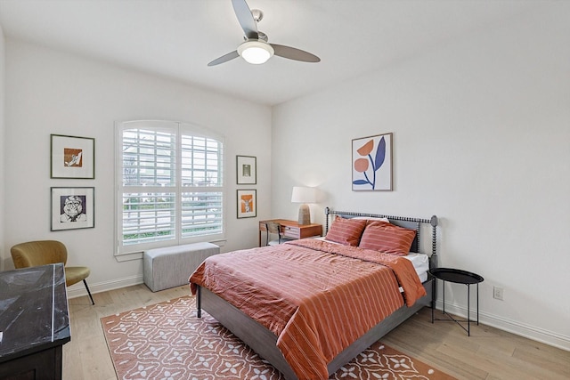 bedroom with ceiling fan, light wood-style flooring, and baseboards