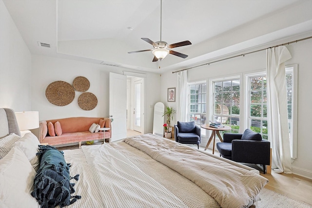 bedroom featuring baseboards, visible vents, a ceiling fan, a tray ceiling, and light wood-type flooring