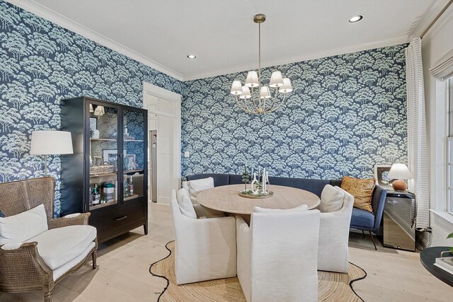 dining space with hardwood / wood-style flooring, ornamental molding, and an inviting chandelier