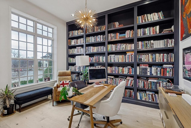 home office with an inviting chandelier, bookshelves, and wood finished floors