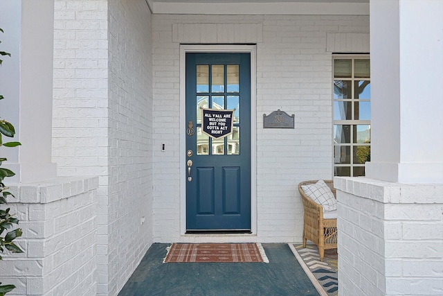 entrance to property featuring a porch and brick siding