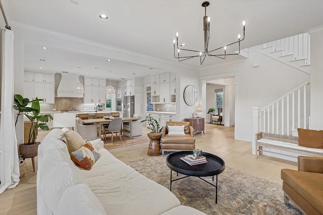 living room with light wood-style floors, recessed lighting, a notable chandelier, and stairway