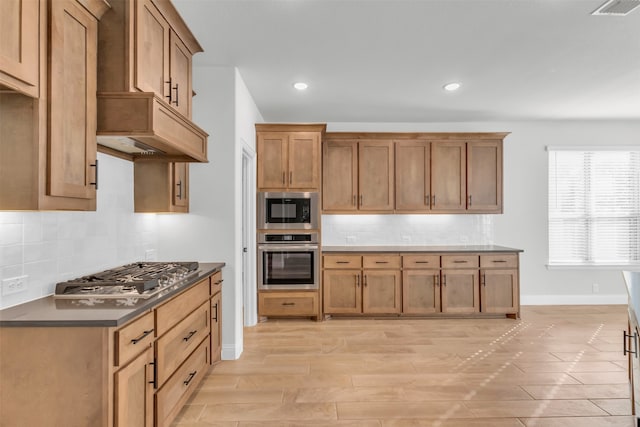 kitchen with tasteful backsplash, appliances with stainless steel finishes, and light hardwood / wood-style flooring