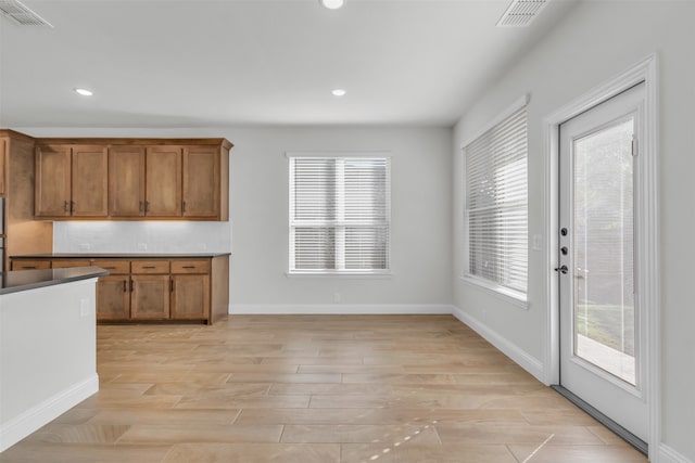 kitchen with tasteful backsplash, a healthy amount of sunlight, and light hardwood / wood-style flooring