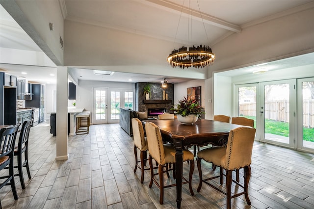 dining space featuring french doors, a fireplace, beam ceiling, and crown molding