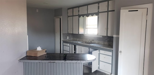 2517 Glencrest Dr, Fort Worth, TX 76119 - kitchen featuring a sink, backsplash, a peninsula, dark countertops, and gray cabinetry