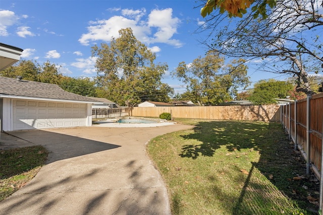 view of yard with a garage and a fenced in pool