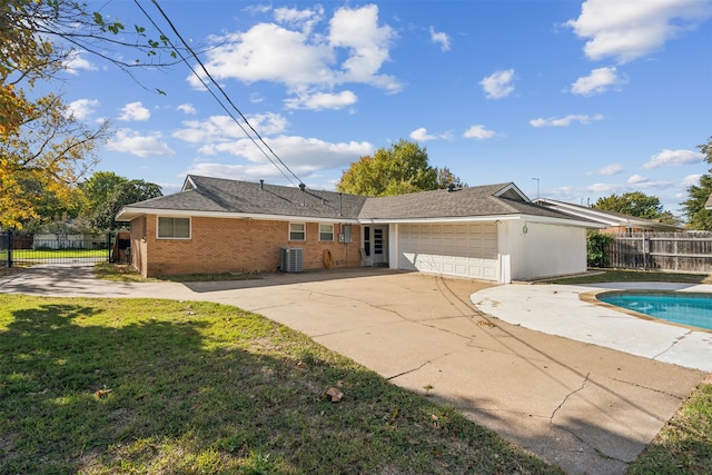 view of front of house with a garage, a front yard, and central AC