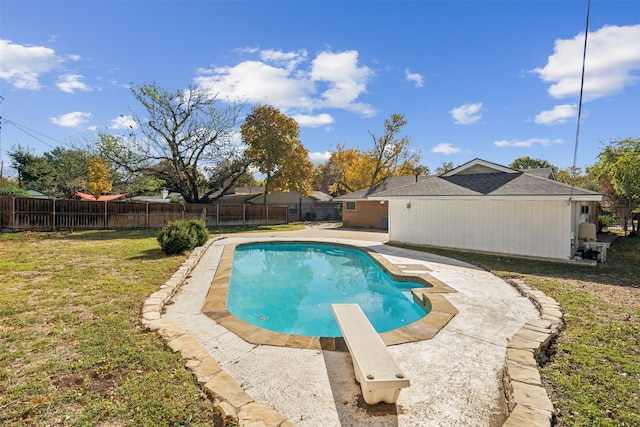 view of swimming pool with a diving board and a yard