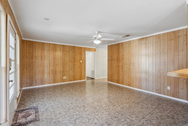 spare room with wooden walls, ceiling fan, and ornamental molding