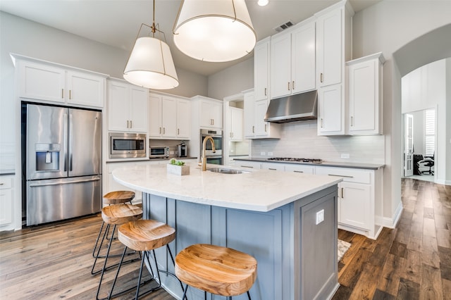 kitchen featuring a breakfast bar area, dark hardwood / wood-style floors, decorative light fixtures, white cabinetry, and stainless steel appliances