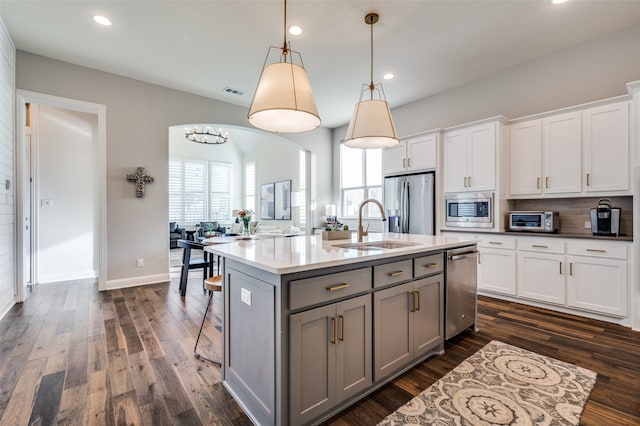 kitchen with pendant lighting, white cabinets, a kitchen island with sink, and appliances with stainless steel finishes