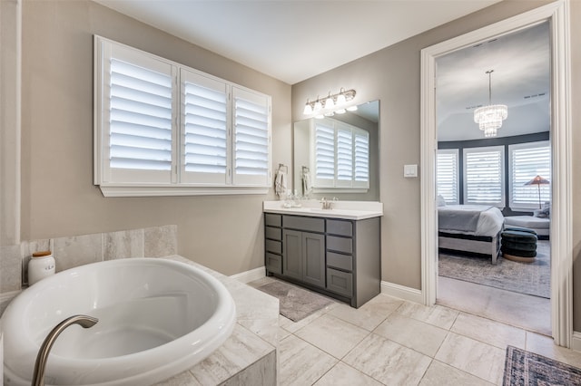 bathroom featuring vanity, tiled tub, and a chandelier