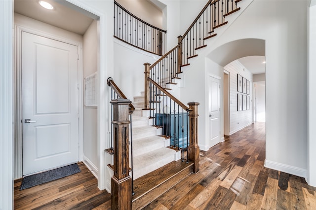 staircase with hardwood / wood-style flooring and a towering ceiling