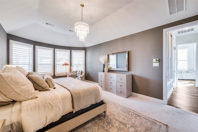 bedroom with hardwood / wood-style floors, lofted ceiling, and a notable chandelier