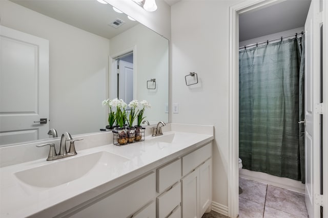 bathroom with toilet, vanity, and tile patterned floors