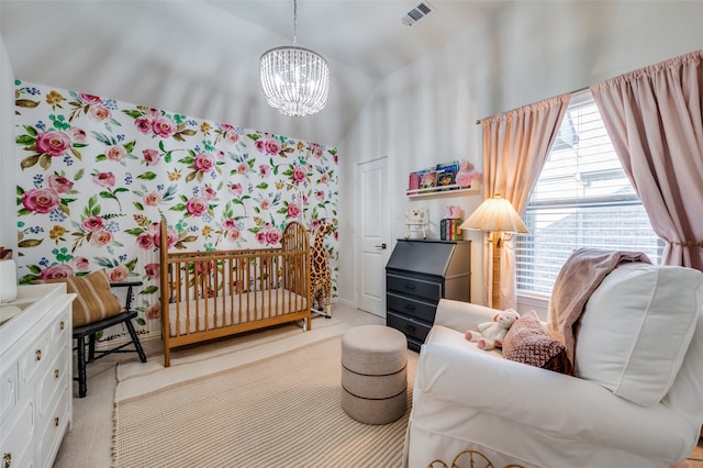 bedroom featuring a crib, lofted ceiling, and a notable chandelier