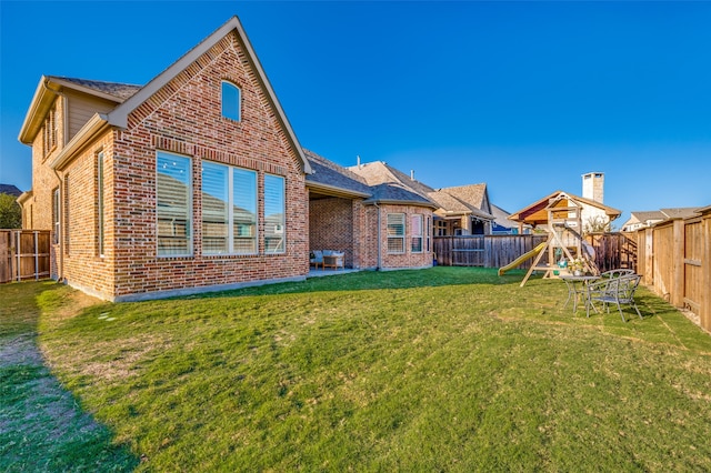 back of property featuring a lawn and a playground