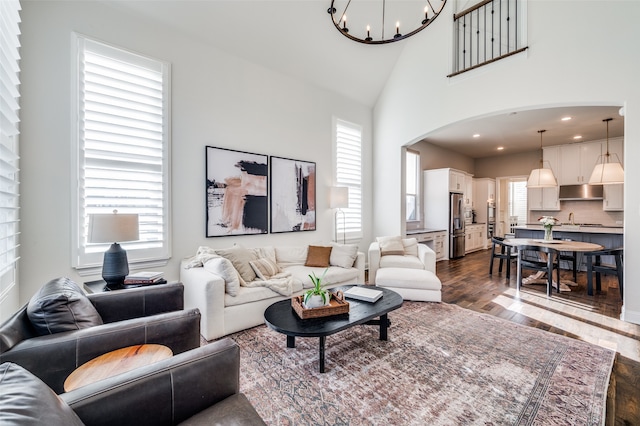 living room with a chandelier, high vaulted ceiling, a healthy amount of sunlight, and dark hardwood / wood-style floors