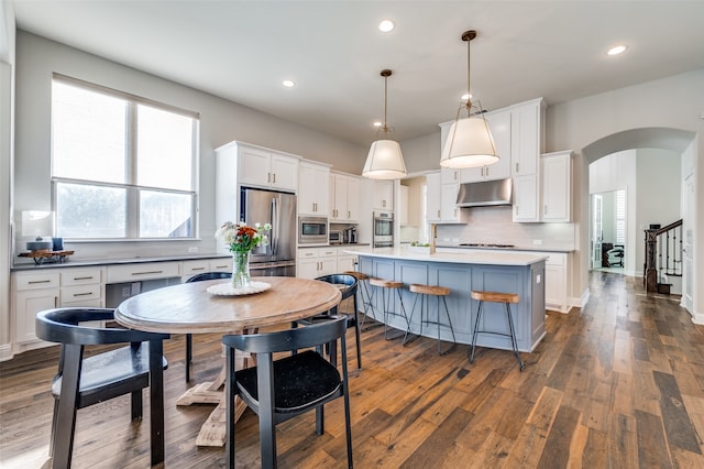 kitchen with pendant lighting, a center island, white cabinets, dark hardwood / wood-style floors, and stainless steel appliances