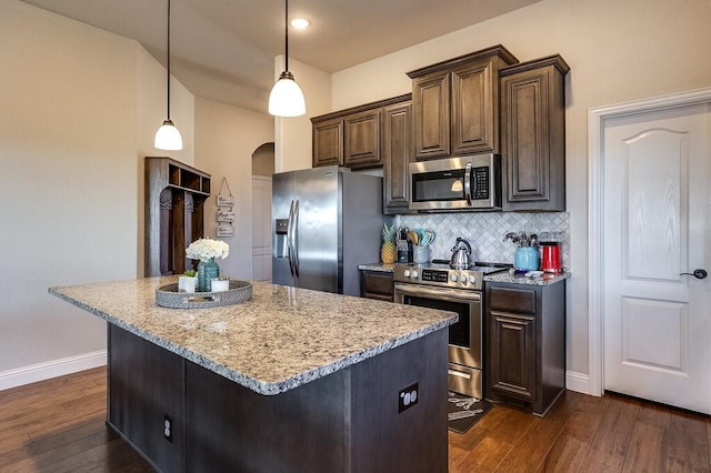 kitchen featuring decorative light fixtures, a kitchen island, dark hardwood / wood-style floors, and appliances with stainless steel finishes