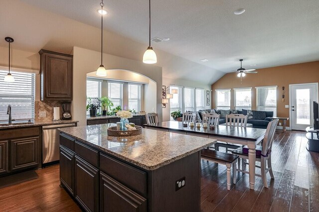 kitchen with a healthy amount of sunlight, a center island, stainless steel dishwasher, and vaulted ceiling