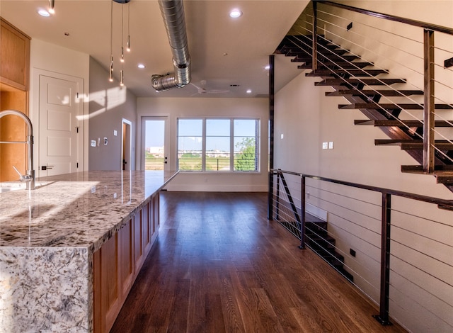 kitchen featuring light stone countertops, dark hardwood / wood-style flooring, decorative light fixtures, and sink