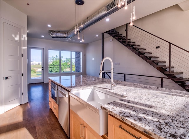 kitchen with light stone countertops, light brown cabinets, dark hardwood / wood-style flooring, and hanging light fixtures