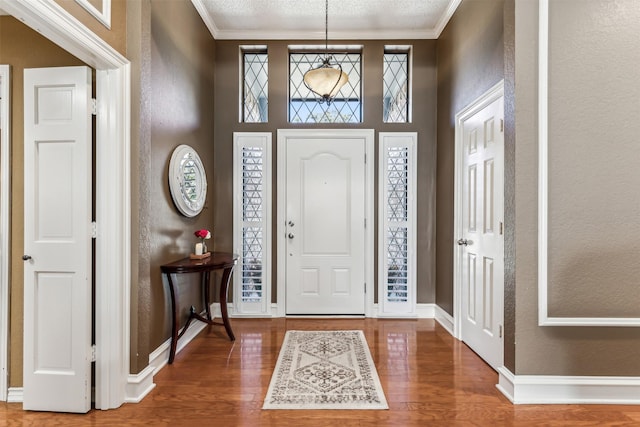 foyer featuring wood-type flooring and crown molding