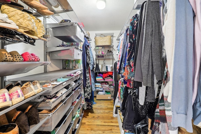 walk in closet with light hardwood / wood-style floors