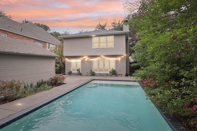 back house at dusk featuring a patio area and french doors